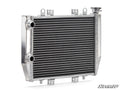 The Up & Running Kawasaki Brute Force 750 Radiator is a shiny, rectangular aluminum ATV radiator with horizontal cooling fins and tubes, left-side inlet and outlet ports, an upper right cap, top and side mounting brackets, and the SuperATV logo at the bot