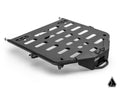 The Assault Industries Kawasaki Teryx KRX 1000 Adventure Rack is a black, sturdy metal cargo carrier with rectangular cutouts, bolts at two corners, a front handle, attachment points, and a logo in the bottom right on a white background.
