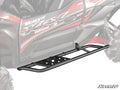 A Kawasaki Teryx KRX 1000 ES in red and black features black metal Tree Kickers with step plates mounted on the sides for protection and easy entry. The SuperATV logo is displayed in the bottom right corner.