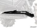 A close-up of black metal Kawasaki Teryx KRX 1000 High-Clearance Rear Trailing Arms installed on an off-road vehicle with large treaded tires and visible suspension; the arms are highlighted while the vehicle appears partially faded.