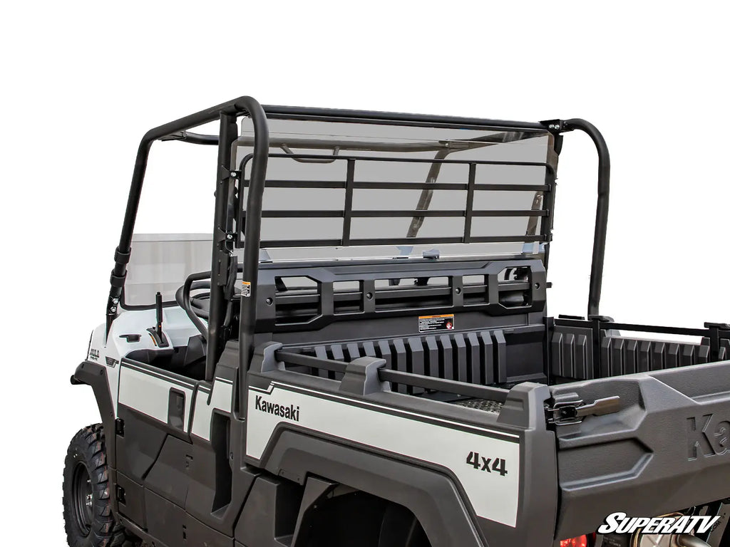 A rear view of a Kawasaki Mule Pro FX with a clear Rear Windshield, open cargo bed, black roll cage, and rugged design is shown against a white background. The SuperATV logo appears in the lower right corner.