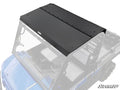 A Kawasaki Mule PRO-FXR Aluminum Roof is mounted on a blue UTV with an open cabin. The rectangular black roof features multiple bolts along its edges and is shown in high detail from an elevated angle.