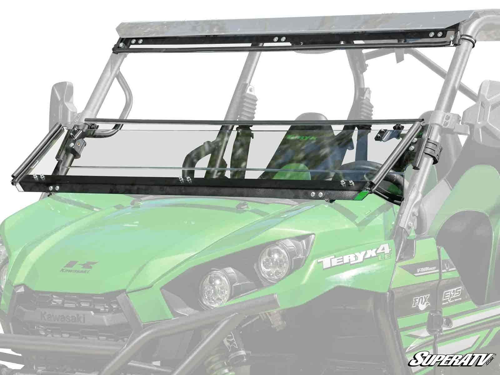 A Kawasaki Teryx4 featuring a green body and a Kawasaki Teryx 3-in-1 Windshield with a hinged, half-open, clear panel mounted on a black metal frame. The SuperATV logo appears in the bottom right corner.