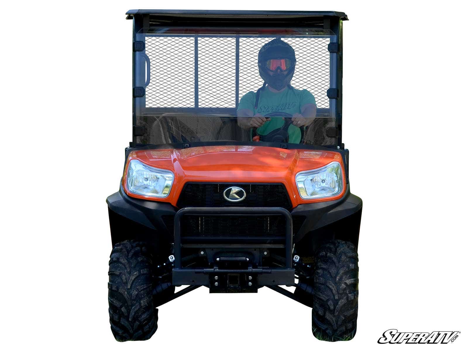A person wearing a helmet sits inside an orange Kubota RTV X900 with a 2 Lift Kit and mesh windshield. The vehicle faces forward, showing large rugged tires, a front bumper, and the SuperATV logo in the bottom right corner.