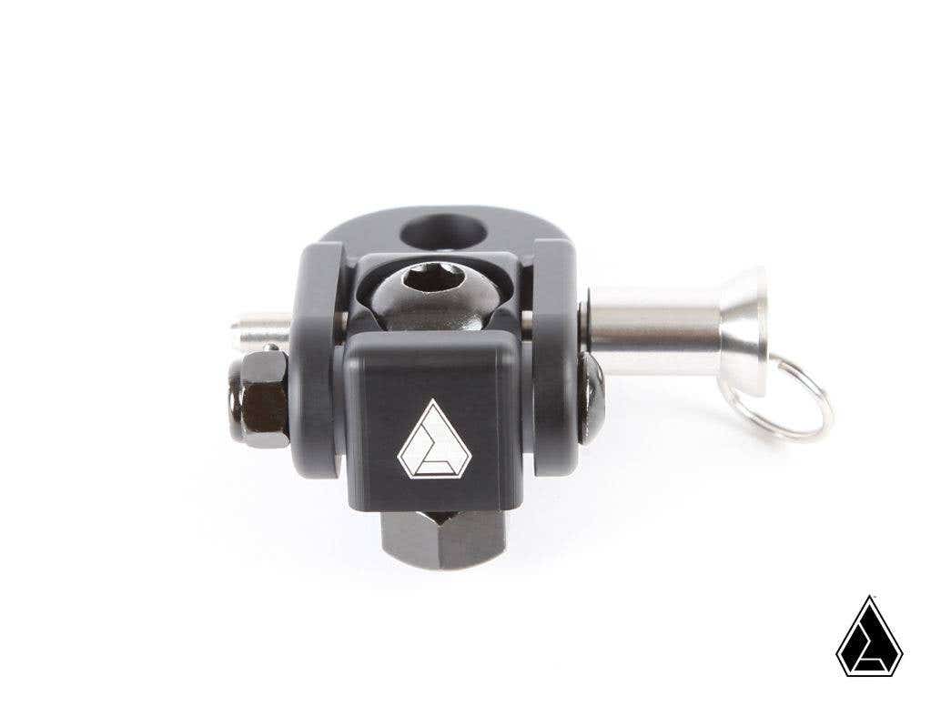 The Assault Industries Quick Release Folding Whip Mount is a small black metal clamp with a geometric logo on the front, featuring a silver bolt and pin with pull ring. It is precisely machined, shown against a white background with the manufacturers logo