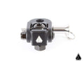The Assault Industries Quick Release Folding Whip Mount is a small black metal clamp with a geometric logo on the front, featuring a silver bolt and pin with pull ring. It is precisely machined, shown against a white background with the manufacturers logo