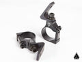 Shown on a white background are two Assault Industries 55deg Top Tube Light Bar Mount Brackets, set of 2, featuring black metal construction with angular design, bolt fastenings, circular openings, and a small triangular logo for mounting lights.