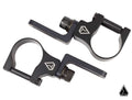 The image shows two Assault Industries 90deg Top Tube Light Bar Mount Brackets (Set of 2) in black metal with circular openings, lever arms, adjustment knobs, and white geometric logos, displayed on a white background with a matching logo.