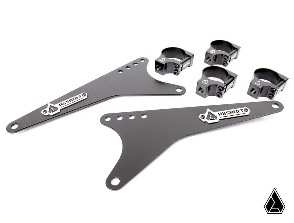 The Assault Industries Extended Light Bar Bracket Kit (Universal) includes two black triangular metal plates with multiple holes, four clamp mounts, and sleek matte finishes. Components feature the Assault logo on metal badges and a small triangular logo 