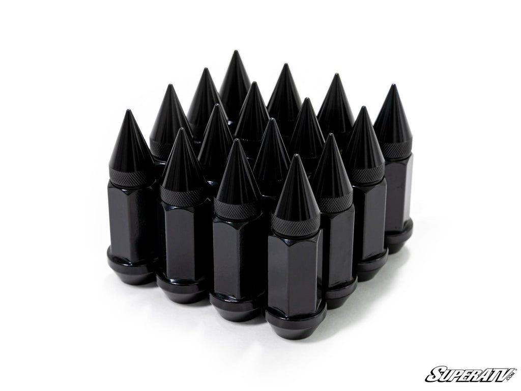 Sixteen glossy black Spiked Lug Nuts, each with a pointed top and faceted sides, are arranged in a tight triangular formation on a white background. The SuperATV logo appears in the bottom right corner.