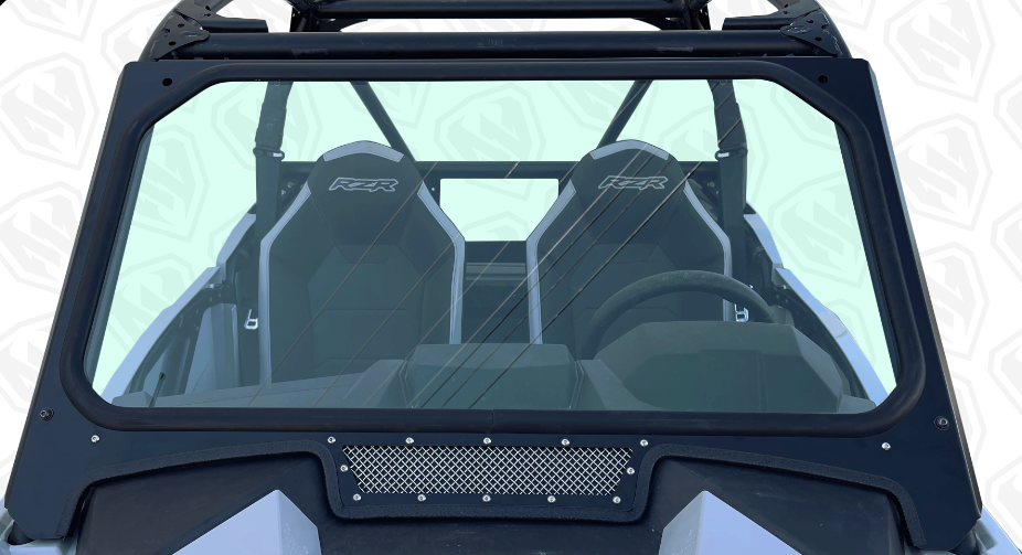 Close-up of the Glass Windshield with Vent for Polaris RZR Trail S, showing two black “RZR” seats, roll cage, steering wheel, and dashboard clearly visible through the windshield.