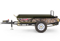 The ATV/UTV Towable Manure Spreader features camouflage-patterned sides, a large black metal cargo bed, a white-rimmed rugged tire, front towing hitch, support leg, and displays the Wallenstein logo.