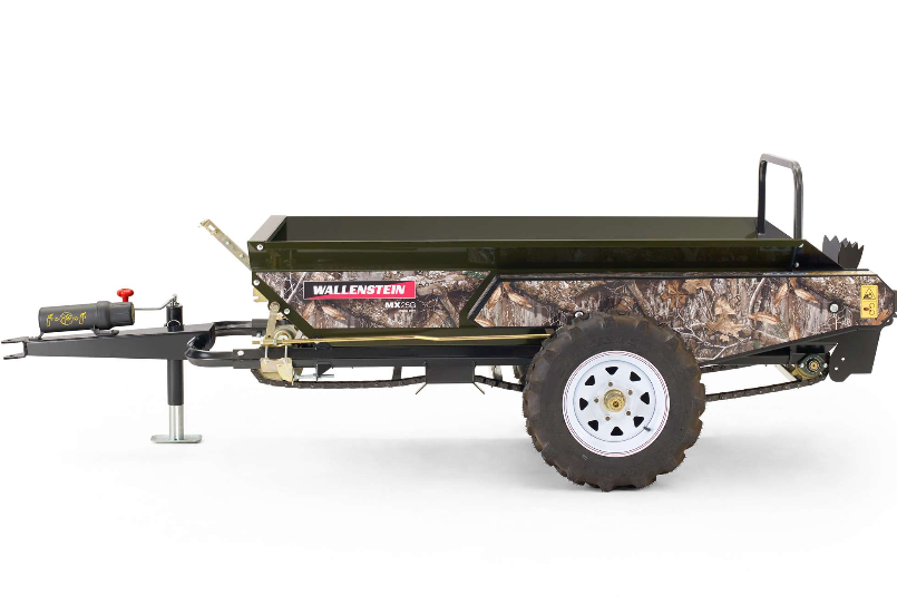 The ATV/UTV Towable Manure Spreader features camouflage-patterned sides, a large black metal cargo bed, a white-rimmed rugged tire, front towing hitch, support leg, and displays the Wallenstein logo.