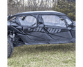 A Can-Am Maverick X3 Max with Soft Upper Doors with Zipper, featuring black clear plastic windows and visible body dents along the side, is parked on grass with bare trees and shrubs in the background.