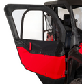 A close-up of the Framed 1/2 Upper Door Kit – Honda Pioneer 1000 shows the red and black off-road vehicle with a partially open soft door, featuring a clear plastic window, black fabric border, and a mesh storage pouch behind the seat.