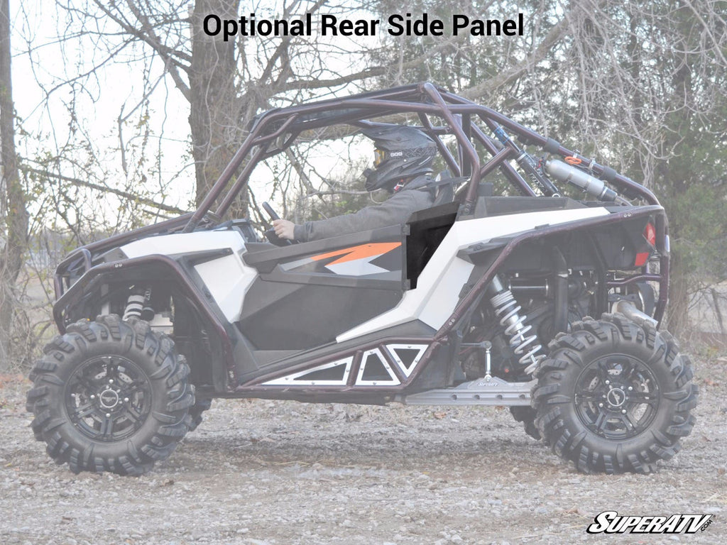 A side view of a Polaris RZR XP Turbo S with rugged tires, roll cage, and helmeted driver displays “Optional Rear Side Panel” above. Trees and dry ground appear in the background, with the SuperATV logo at bottom right. Lower Doors are featured.