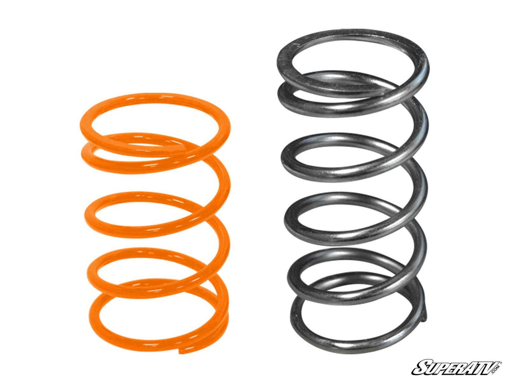 Two metal coil springs stand upright side by side on a white background. The left spring is orange and shorter with tighter coils; the right is silver, taller, and spaced wider. The “SuperATV” logo appears at bottom right. For Polaris Ranger XP 900 Clutch