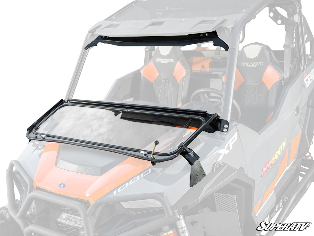 A color photo of a Polaris General 1000 with a Flip-Down Glass Windshield partially open. The UTV features orange and black seats, a black windshield frame with metal brackets, and the SuperATV logo at the bottom right.