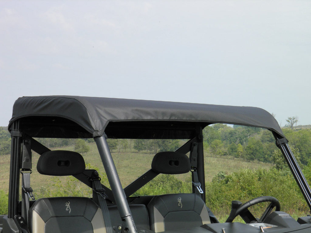 A Polaris General Soft Top covers the roof of a two-seat off-road utility vehicle parked outdoors near grassy terrain and trees under a partly cloudy sky.