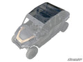 The Polaris General 4 Seater Tinted Roof, made from black-tinted polycarbonate, is installed on a four-seater off-road vehicle. Its partial transparency accentuates the roof’s fit and coverage, with the SuperATV logo in the bottom right corner.