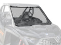 The Polaris RZR Pro R Scratch-Resistant Full Windshield is mounted on a black side-by-side, covering the entire front. It features mounting brackets, an edge rubber seal, and displays the SuperATV logo in the bottom right corner.