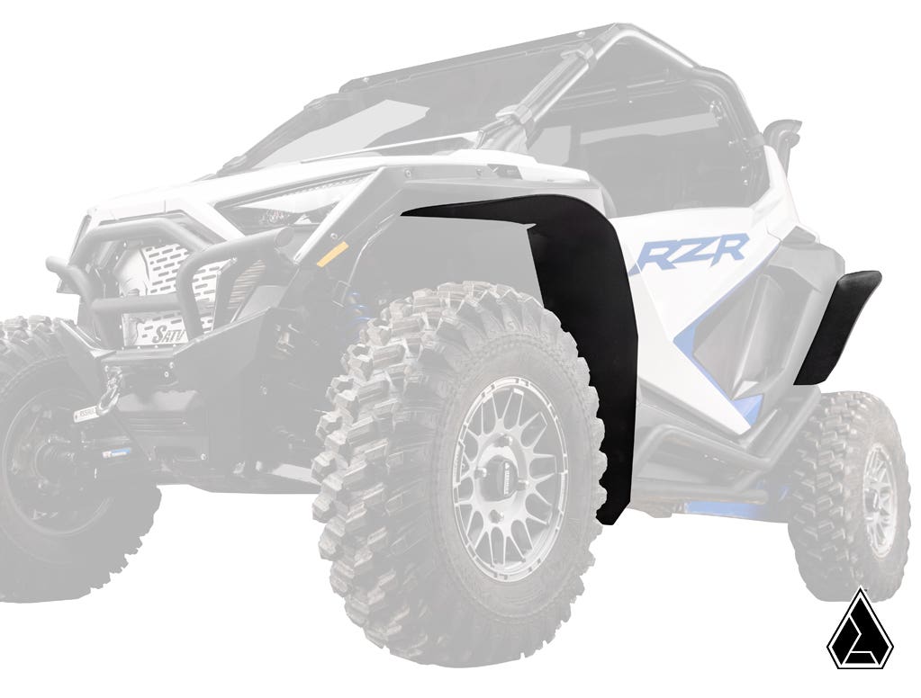 A white and blue Polaris RZR PRO XP with large treaded tires is pictured. The Assault Industries Low-Profile Fender Flare on the driver’s side front is highlighted in black, while the rest of the vehicle fades. A small angular black logo appears at bottom