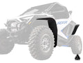 A white Polaris RZR Pro R with oversized tires and partially faded paint features Assault Industries Low-Profile Fender Flares in black on the front and rear wheel wells. The RZR logo is visible on the side; a small black logo is at bottom right.