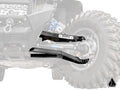 A close-up of a Polaris RZR PRO XP’s suspension featuring Assault Industries High-Clearance 1.5 Forward Offset Boxed A-Arms with a bold “ASSAULT” label, the guard in sharp focus and an angled triangle logo at the bottom right.