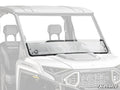 A Polaris Ranger XD 1500 Half Windshield with a horizontal seam, rubber seal, and a circular left-side vent is mounted on a white utility vehicle. The clear glass covers the front; the background and interior are faintly visible.