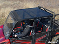 Wearing a black helmet and jacket, a person drives a red and black Polaris Ranger XP 570 Crew with a tinted roof across dry grass. The seats say “PRP,” and the image is watermarked “SuperATV” in the lower right corner.