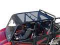 A person in a black helmet and jacket drives a red Polaris Ranger XP 1000 Crew with a tinted roof, open sides, two seats, protective bars, and SuperATV branding on the lower right. The background is white.
