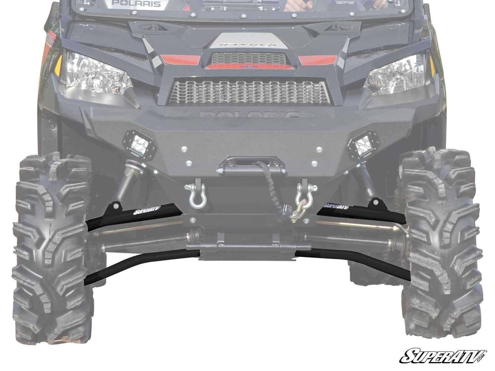 Close-up front view of a black off-road ATV showcasing rugged tires, winch, suspension, and Polaris Ranger XP 570 High Clearance 1.5 Forward Offset A-Arms. Two square LED lights are visible. SuperATV logo at bottom right; background faded to emphasize fro