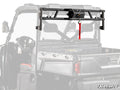 A sturdy black Polaris Ranger 1000 Diesel Game Loader Rack with a red strap and lock is mounted to the rear bed of a utility side-by-side. The faded background highlights the metal rack and “SuperATV” logo in the bottom right corner.