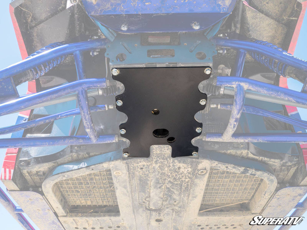 View from below shows a Polaris Ranger Frame Stiffener, newly installed with bolts. The black metal plate is mounted under the vehicle, with blue suspension arms and a dusty chassis visible. The SuperATV logo appears in the bottom right corner.