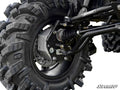 Close-up of a Polaris Ranger Full-Size 800 4 Portal Gear Lift’s large, knobby tire and suspension system, showing thick rubber treads, metal axle, springs, and drive shaft. The SuperATV logo is printed on a metal bar in the upper right corner.