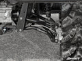 Close-up of Polaris Ranger High Clearance Rear A-Arms’ suspension system with black control arms, visible shock absorber, and rugged tire on gravel. SuperATV branding appears on the A-arm and in the image corner.