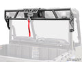 A Polaris Ranger EV Game Loader Rack, made of black steel with a winch and red tow strap, is mounted on the back of a UTV. The rack features integrated LED lights on both sides, with the UTV bed and roll cage partially visible behind it.