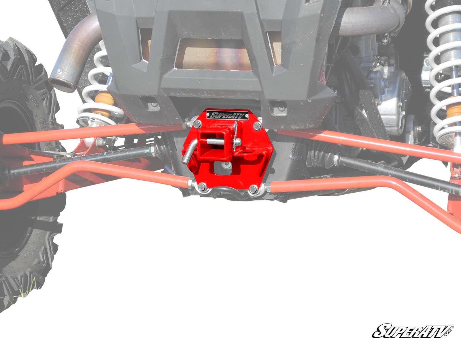 Close-up of a Polaris RZR XP Turbo Rear Receiver Hitch attached to orange suspension arms, with coil springs and a large tire visible. The hitch and vehicle parts are the main focus against a white background.