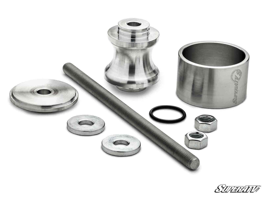 The Polaris Wheel Bearing Removal Tool set includes silver-colored metal parts—a threaded rod, two hex nuts, two washers, a spacer, a domed cap, a spool-shaped piece, a rubber O-ring, and a SuperATV-branded cylinder—displayed on a white background.