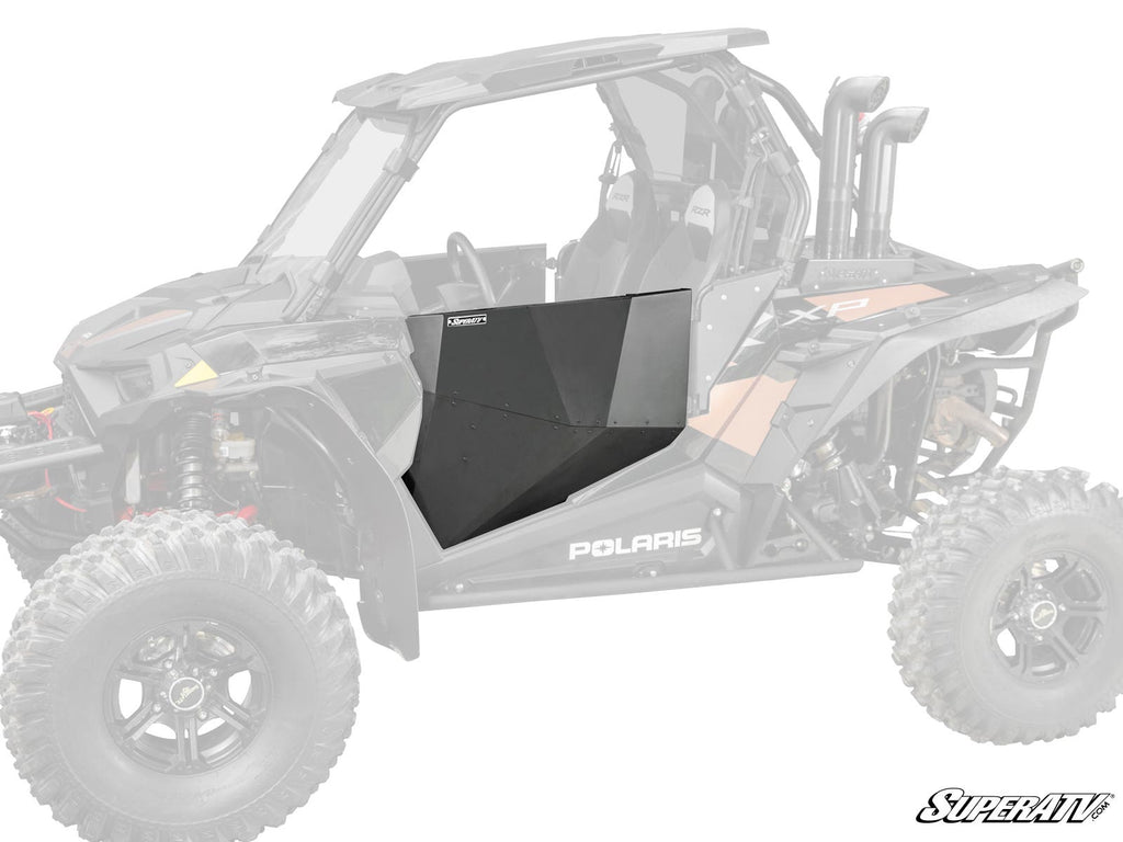 A black, angular Polaris RZR XP Turbo Aluminum Door Skin is installed as a side door on a Polaris off-road vehicle, with the rest of the vehicle faded to highlight the panel. The SuperATV logo is in the bottom right corner.