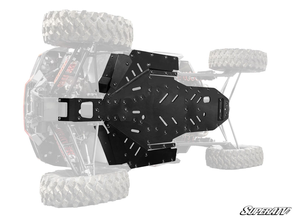 This image highlights the Polaris RZR XP Full Skid Plate installed on the underside of an off-road vehicle, protecting its chassis. The skid plate is emphasized while the rest of the vehicle fades, with the SuperATV logo in the bottom right.