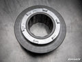 A close-up view of a Polaris RZR Billet Torsion Spring Retainer, a circular metal automotive part with a textured inner ring and notched outer rim, rests on a scratched metal surface. The SuperATV logo appears in the bottom right corner.