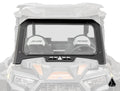 A clear, rectangular Assault Industries Polaris RZR XP Turbo Glass Windshield with a black frame is mounted on a Polaris RZR side-by-side vehicle, showing two RZR-labeled seats and the manufacturers logo in the lower right corner.
