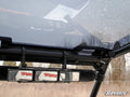 Close-up of a Polaris RZR 900 Tinted Roof interior, featuring a three-panel rearview mirror on a black roll cage. Trees and cloudy sky are visible through the windshield. “SuperATV” logo appears in the lower right corner.