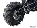 Close-up of a Polaris RZR XP 900 4 Portal Gear Lift installed, showing a rugged off-road tire with deep treads covered in mud and dirt. Branded components, visible shock absorber, and SuperATV logo featured in the bottom right corner.