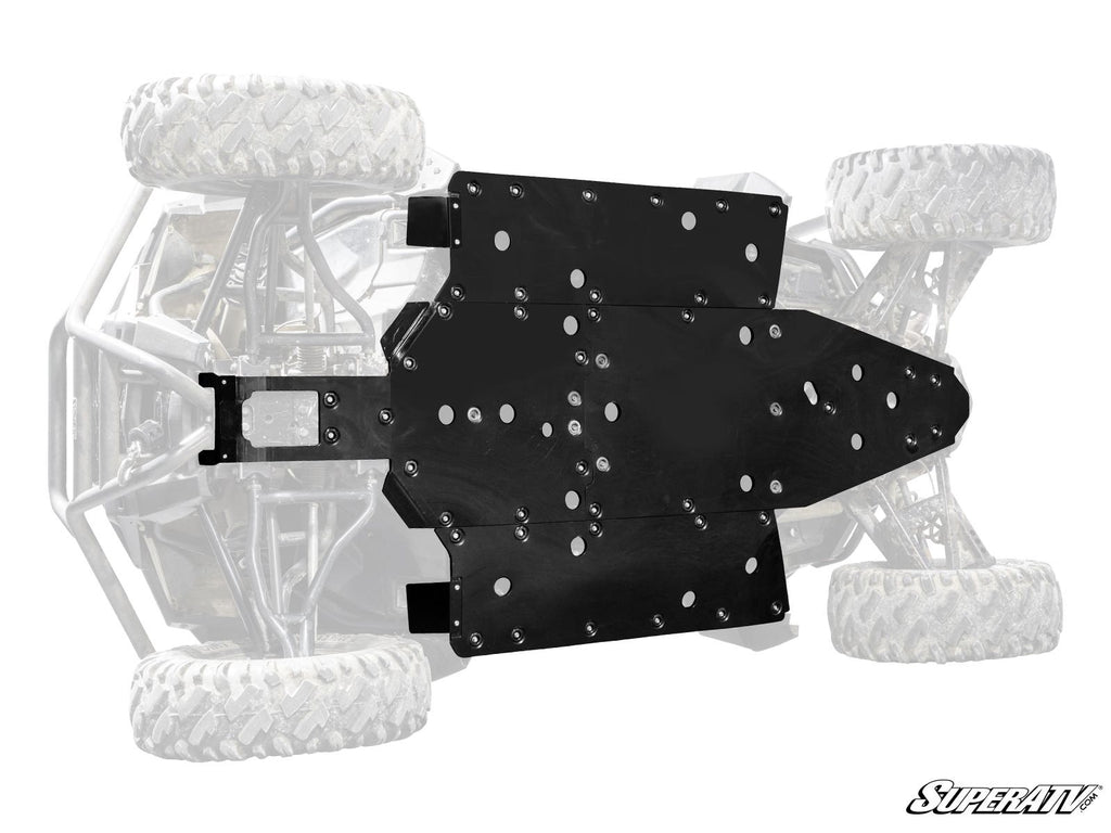 A Polaris RZR Trail 900 Full Skid Plate is attached to the underside of an off-road vehicle in partial grayscale. The black metal plate features multiple bolt holes for protection, with the SuperATV logo in the bottom right corner.