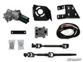 The Polaris RZR XP 1000 Power Steering Kit is displayed on a white background with an electric motor, two black mounting brackets, wiring harness, metal plate, hardware in bags, electronic control unit, two black steering shafts, and the SuperATV logo in 