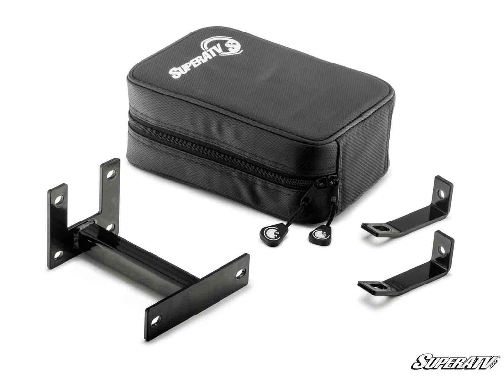 A Polaris RZR Armrest Gun Safe in black with a zipper is shown alongside three black metal mounting brackets of different shapes, all on a white background. The SuperATV logo appears on the safe and in the bottom right corner.