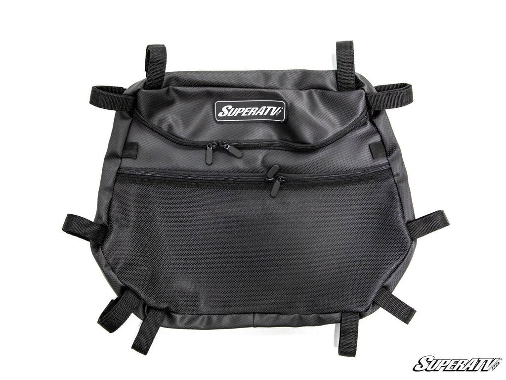 The Polaris RZR Overhead Storage Bag is black with the SuperATV logo, features a main zippered compartment, a smaller front zippered pocket, a mesh front pocket, and multiple adjustable straps for secure attachment. Displayed on a white background.