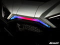 Close-up of a white Polaris RZR PRO XP Front Accent Light with an angular LED strip—blue left, red center, purple right. Black grille and SuperATV logo at bottom right give it a modern, sporty look.